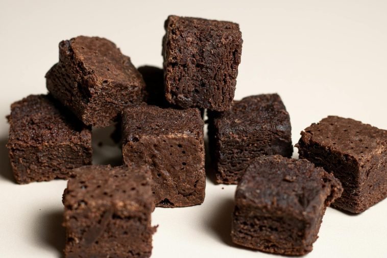 Close-up of rich chocolate brownie cubes on a neutral background, perfect for dessert lovers.