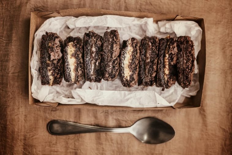Close-up of rich chocolate brownies in a box on a rustic surface. Perfect for dessert lovers.