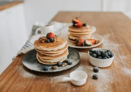 Mouth-watering pancakes topped with strawberries, blueberries, and walnuts.