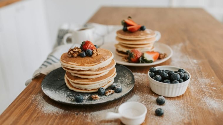 Mouth-watering pancakes topped with strawberries, blueberries, and walnuts.