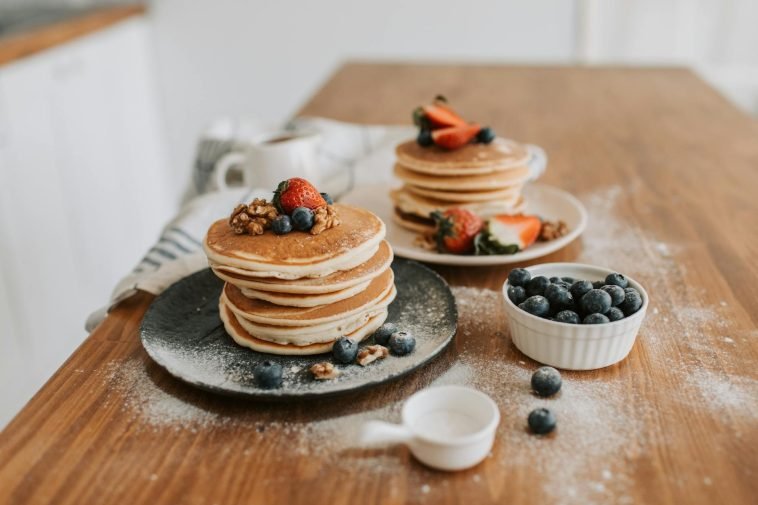 Mouth-watering pancakes topped with strawberries, blueberries, and walnuts.