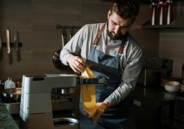 Chef expertly makes fresh pasta in a professional kitchen using a pasta machine.