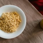A delicious serving of instant noodles in a white bowl with chopsticks on a textured table.