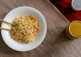A delicious serving of instant noodles in a white bowl with chopsticks on a textured table.