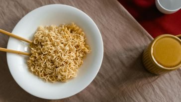 A delicious serving of instant noodles in a white bowl with chopsticks on a textured table.
