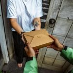 A delivery person handing over a package to a customer at their doorstep.
