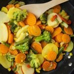 A vibrant mix of stir-fried vegetables including broccoli and carrots in a frying pan.
