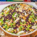 Colorful salad with black beans, corn, and cabbage mix in a decorative brass bowl.