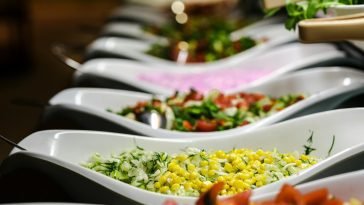 A vibrant selection of salads served in elegant ceramic dishes at a buffet.