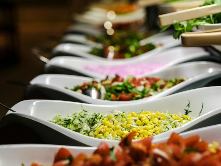A vibrant selection of salads served in elegant ceramic dishes at a buffet.