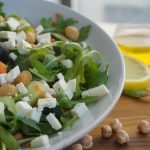 A colorful Mediterranean salad featuring feta, olives, chickpeas, and fresh greens.