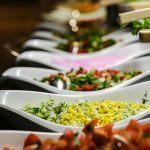 A vibrant selection of salads served in elegant ceramic dishes at a buffet.