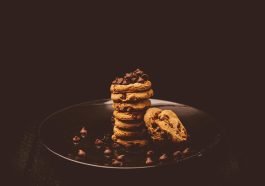 Delectable stack of chocolate chip cookies on a dark plate, perfect for dessert lovers.