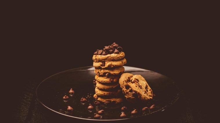 Delectable stack of chocolate chip cookies on a dark plate, perfect for dessert lovers.