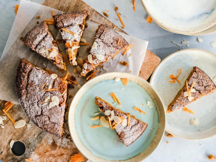Top-down view of rustic orange almond cake slices on ceramic plates, perfect for dessert lovers.