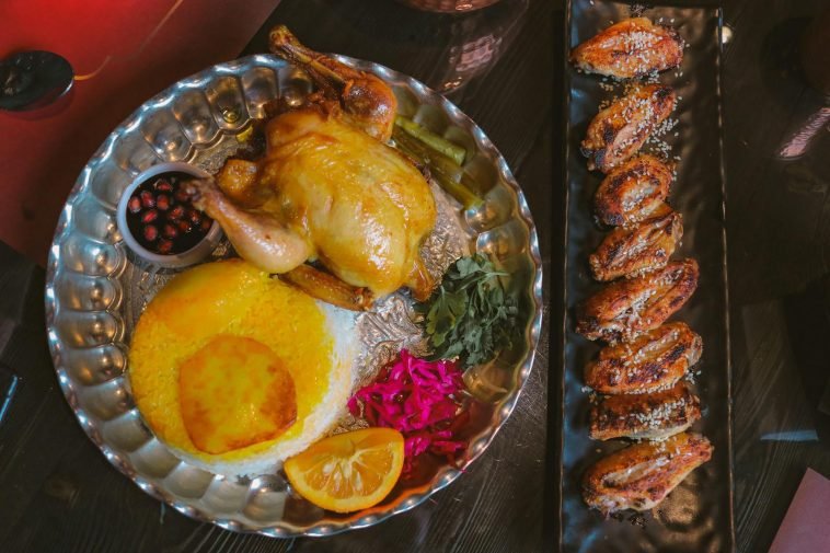 A gourmet Persian meal featuring roast chicken, saffron rice, and assorted sides. Ideal for foodies.