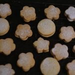 A batch of freshly baked shortbread cookies cooling on a rack, dusted with powdered sugar.