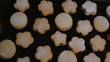 A batch of freshly baked shortbread cookies cooling on a rack, dusted with powdered sugar.
