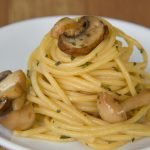 Appetizing mushroom pasta on a white plate, featuring a close-up view of the culinary delight.