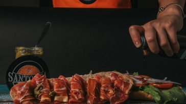 Close-up of a gourmet sandwich being prepared with fresh ingredients and sauces.