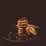 Delectable stack of chocolate chip cookies on a dark plate, perfect for dessert lovers.
