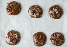 Top view of chocolate cookies with chunks on baking sheet.