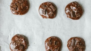 Top view of chocolate cookies with chunks on baking sheet.