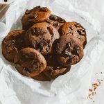 A tempting pile of homemade chocolate chip cookies on a parchment paper, perfect for dessert lovers.