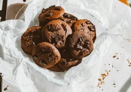 A tempting pile of homemade chocolate chip cookies on a parchment paper, perfect for dessert lovers.