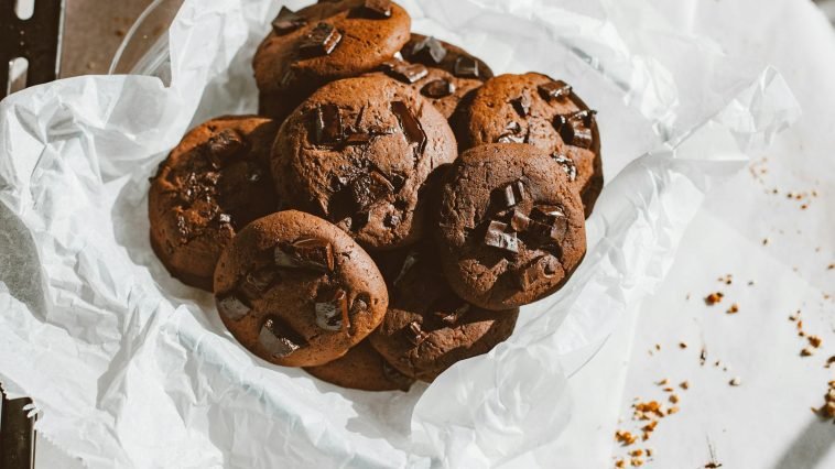 A tempting pile of homemade chocolate chip cookies on a parchment paper, perfect for dessert lovers.