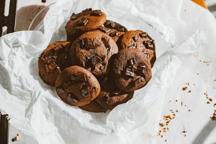 A tempting pile of homemade chocolate chip cookies on a parchment paper, perfect for dessert lovers.