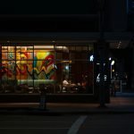 Captured at night, a vibrant Houston cafe with colorful mural through the window, evoking a lively yet calm evening vibe.