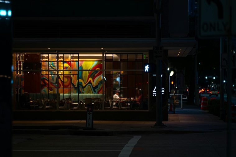 Captured at night, a vibrant Houston cafe with colorful mural through the window, evoking a lively yet calm evening vibe.