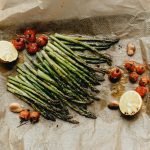 Delicious roasted asparagus with cherry tomatoes and lemon on parchment paper, perfect for a healthy meal.