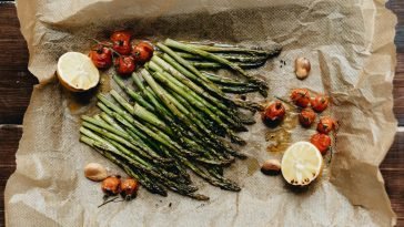 Delicious roasted asparagus with cherry tomatoes and lemon on parchment paper, perfect for a healthy meal.