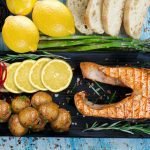 Delicious grilled salmon served with lemon slices, potatoes, and asparagus on rustic table.