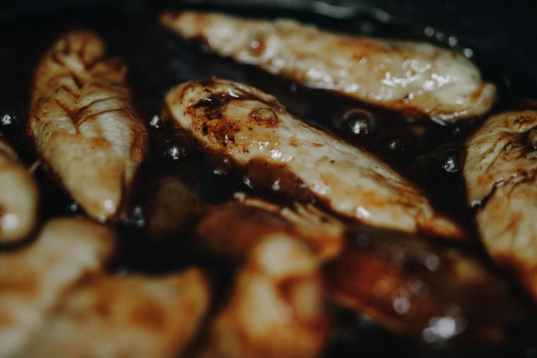 Delicious marinated chicken pieces sizzling in a pan, perfect for a hearty meal.