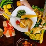 A top view of a roasted chicken dinner with fresh vegetables and citrus garnishes, perfect for festive gatherings.