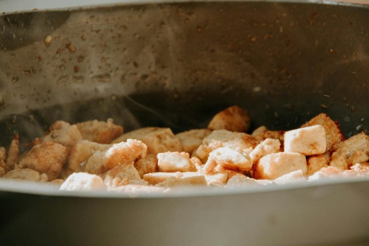 A close-up view of tofu cubes being cooked in a frying pan.