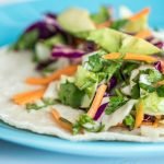 Close-up of a vibrant taco with fresh vegetables on a blue plate.