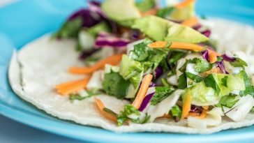 Close-up of a vibrant taco with fresh vegetables on a blue plate.