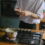 A person takes pictures of a boiling pot on a stove, capturing culinary moments.
