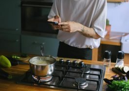 A person takes pictures of a boiling pot on a stove, capturing culinary moments.