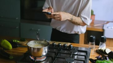 A person takes pictures of a boiling pot on a stove, capturing culinary moments.
