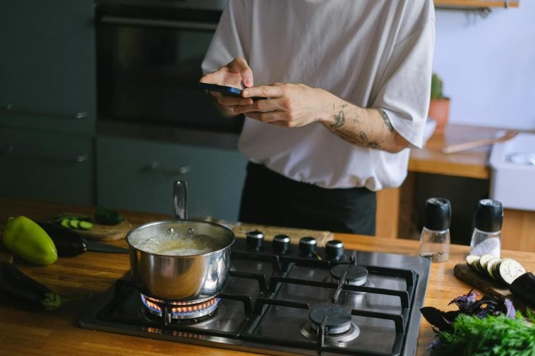 A person takes pictures of a boiling pot on a stove, capturing culinary moments.