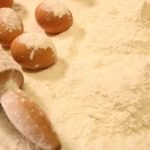 Close-up of baking ingredients including eggs, flour, and a rolling pin.