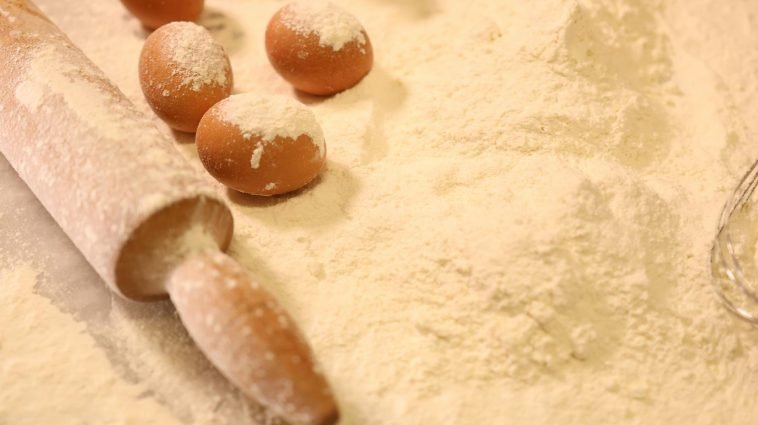 Close-up of baking ingredients including eggs, flour, and a rolling pin.