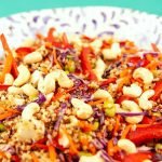 Colorful quinoa salad with red cabbage, cashews, and bell peppers in a ceramic bowl.