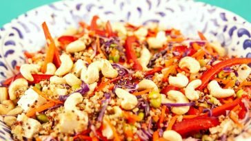 Colorful quinoa salad with red cabbage, cashews, and bell peppers in a ceramic bowl.