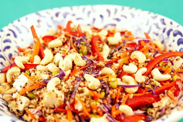 Colorful quinoa salad with red cabbage, cashews, and bell peppers in a ceramic bowl.